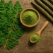 Moringa w liściach i sproszkowana, w miseczce.